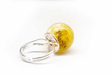 Round metal base of a ring closeup. Back side of a piece of handmade jewelry. Bright yellow flowers in epoxy resin. Selective focus on the details, object isolated on white background.