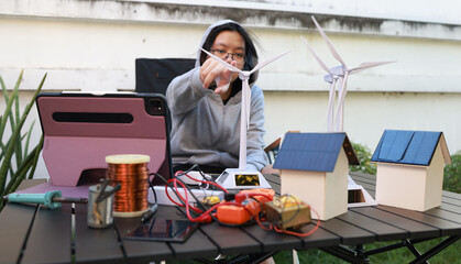 Young girl learn and practice solar cell and wind turbine , science edudation concept . Selft...