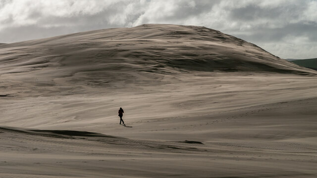 A woman walking into strong winds on sand dune