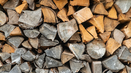 Cut wood logs stored in a storage yard. This woodpile are chopped and saved to burn in a stove during winter.