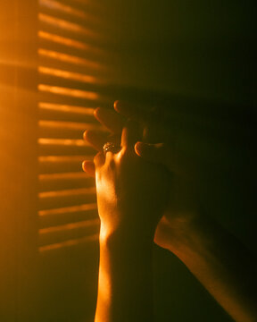 Man and woman holding hands in front of window blinds. 