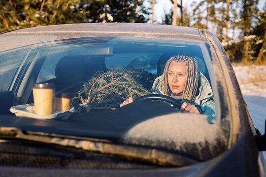 Woman driving through forest with a fir tree and coffee