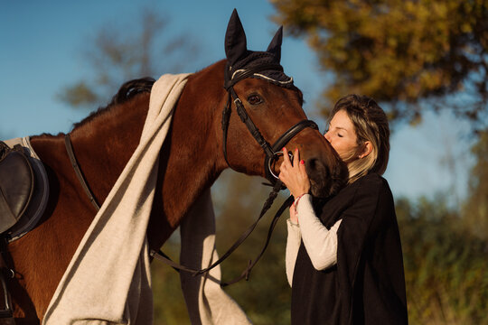 Woman kisses her horse on the muzzle