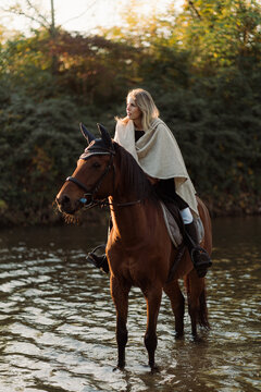 Woman on horseback fords a river to continue the trip