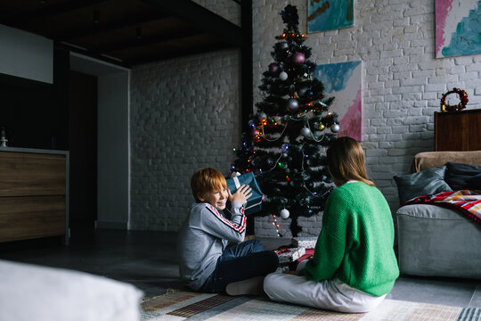 Young boy excited to opening Christmas gift with sister