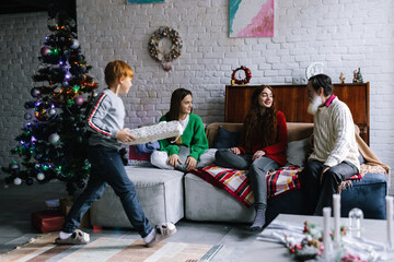 Male teen bring present from Christmas tree to family