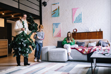 Happy little boy helping grandpa carry Christmas tree