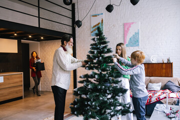Family installing Christmas tree into cozy room 