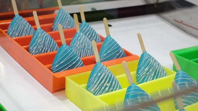 Blue sweet cake pops on the bright colorful showcase, confectionery for party events, funny desserts