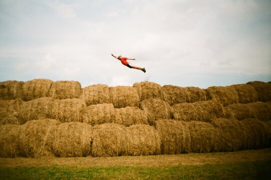 Man flying like superhero above haystacks