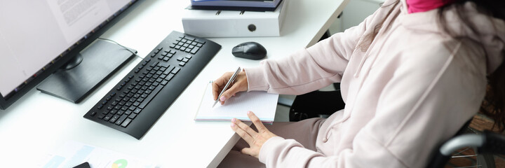 Woman in wheelchair works at computer in workplace