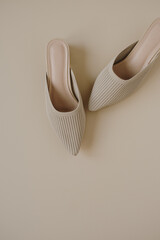 Flat lay of trendy female shoes on neutral pastel beige background. Aesthetic luxury fashion accessory. Top view