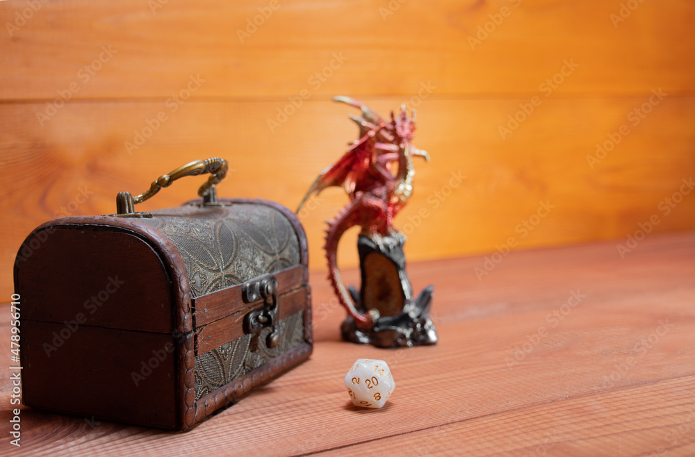 Wall mural Ivanovo, Russia - 02.11.2021: Selective focus on D20 white dice,  blurry toy miniature of dragon and  storage box for playing Dungeons and Dragons role-playing game on wooden background