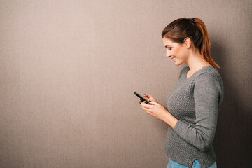 Trendy young woman with ponytail using a smartphone