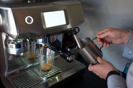 Woman frothing milk for latte coffee