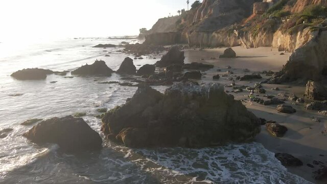 Aerial view of rocks, waves and people walking at El Matador Beach in Malibu California