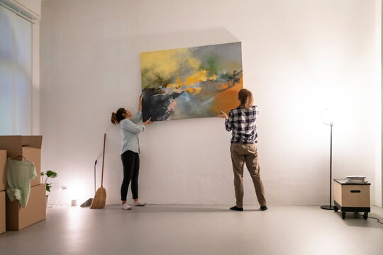 Happy diverse couple carrying colorful painting