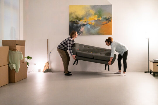 Couple carrying couch in new apartment