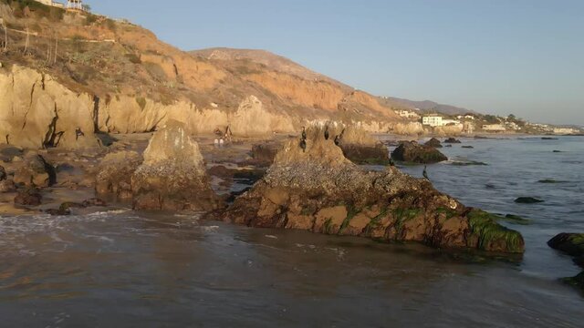Aerial view of birds standing on a sea stack at El Matador beach with people walking on the shore, North Pacific Ocean Malibu California
