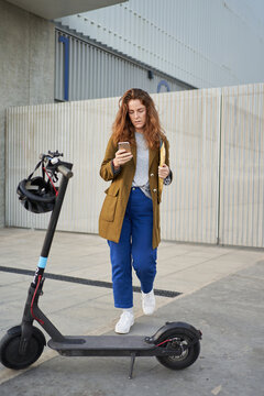 Businesswoman using smartphone near e scooter