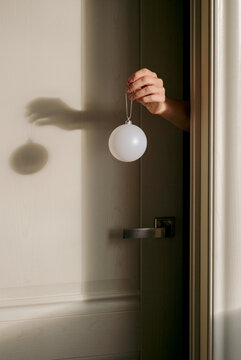 Hand holds out Christmas plastic ball  through the door