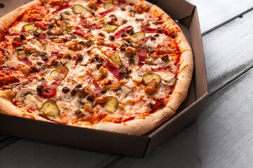 Pizza in a cardboard box with a variety of fillings close-up. Italian cuisine