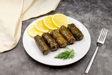Stuffed grape leaves with olive oil on a dark background. Traditional Turkish cuisine delicacies. Delicious dolma (yaprak sarma). Horizontal view. Close up