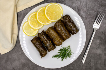 Stuffed grape leaves with olive oil on a dark background. Traditional Turkish cuisine delicacies. Delicious dolma (yaprak sarma). Top view. Close up