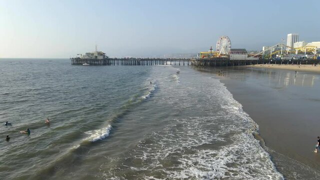 People swimming in the ocean at Santa Monica California with view of theme park at the pier