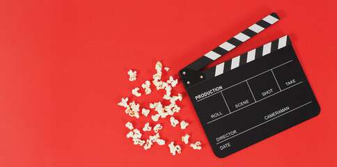 Fototapeta na wymiar Black Clapper board or movie slate and popcorn on a red background.