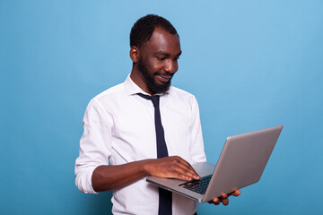Portrait of relaxed businessman holding laptop looking at screen browsing social media. Smiling entrepreneur in videocall conference on wireless portable computer.