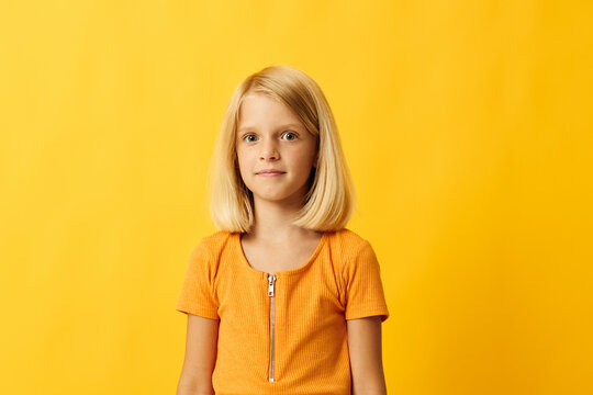 cute little girl with blond hair posing yellow background