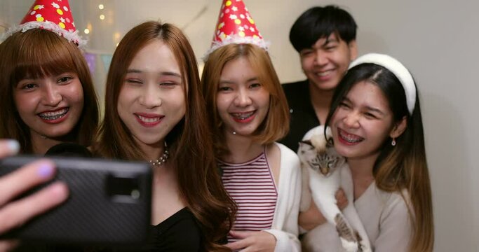Group of happy Asian friends making video call with smartphone at home party.