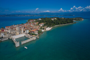 Fototapeta na wymiar Aerial view on Sirmione sul Garda. Italy, Lombardy. Rocca Scaligera Castle in Sirmione. View by Drone. Boat with tourists near the main castle.