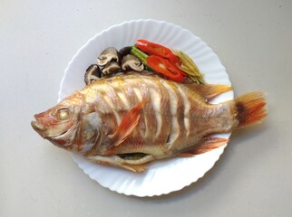 Steamed Red Tilapia with soy sauce on white dish.Top view