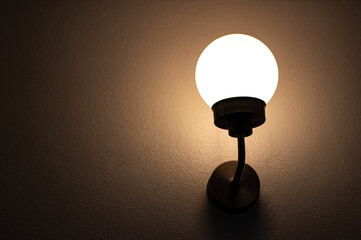 Vintage electric lamp is installed with the wall and turned on in the dark night