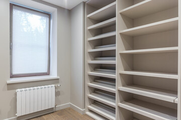 Dressing room is a bright room with a window and built-in wardrobes for storing clothes and shoes.