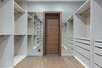A dressing room in blue tones with a brown door and lots of wardrobes for storing clothes.