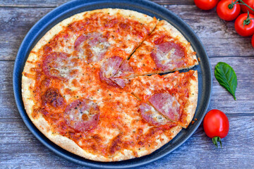 Home made italian  pepperoni   pizza with  tomatoes, mozzarella and parmesan cheese and fresh basil  on wooden background