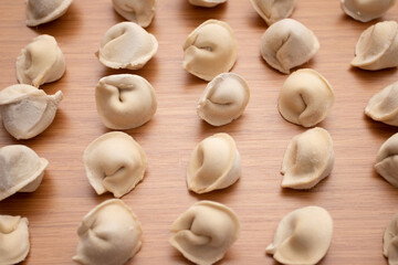 Fototapeta na wymiar Fresh uncooked dumplings pelmeni on a wooden board