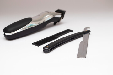 Black straight razor and electric trimmer on a white background