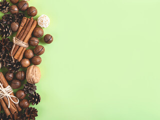 Christmas or New Year natural composition of nuts and cones in the form on the green background. Beige and green natural design.