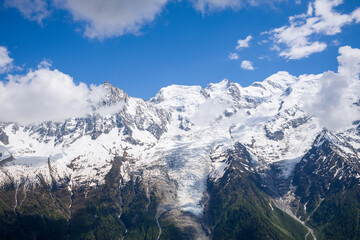 The Mont Blanc Massif and white clouds in the Mont Blanc Massif in Europe, France, the Alps, towards Chamonix, in summer on a sunny day.