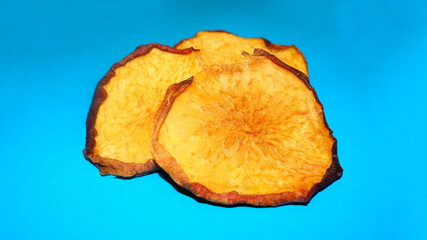 dried peach chips lie on a blue background. side view. healthy homemade food. dried fruits