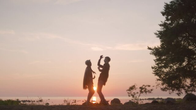Handheld cinematic shot of couple dancing on beach at sunset. Romantic and sensual couple perform an interpretative dance in soft setting sun light. Conceptual modern love