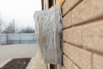 Broken electric meter wrapped in duct tape on the wall