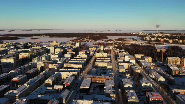 Aerial view of sunlit, winter streets of sunny Oulu city - tracking, drone shot