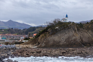 Fototapeta premium zumaia lighthouse on cliff with town in the background
