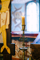 Obraz na płótnie Canvas Wax candle on a candlestick near the crucifix in the temple
