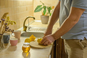  man cuts a lemon to prepare a medicinal drink for a cold for his loved one: child, wife, mother. treating colds at home with folk remedies